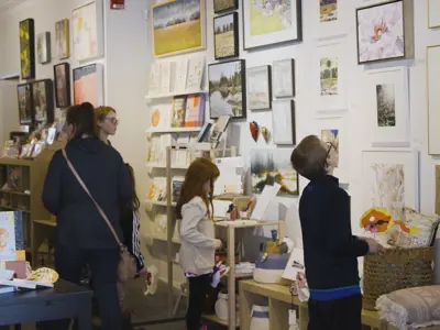 Families in the Art Gallery of Peterborough's gallery shop looking at different items on the walls.