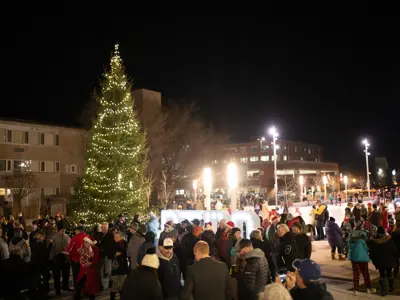 Holiday Tree Lighting Event at Quaker Foods City Square in Peterborough, crowds of people with festive tree and ice rink in the background